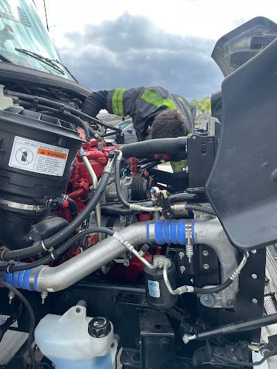 A man is working on the engine of a truck.