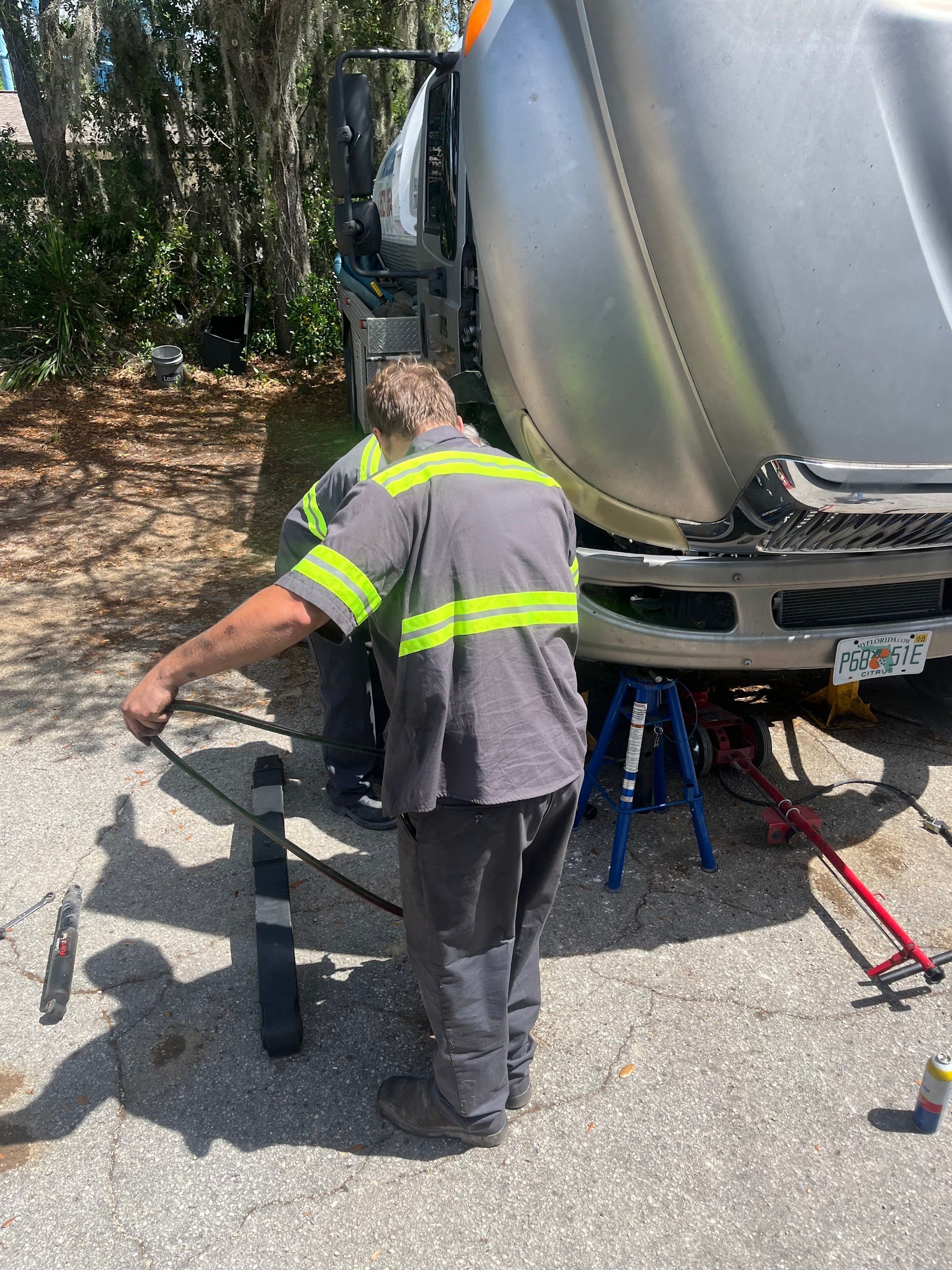 A man in a safety vest is working on a truck.