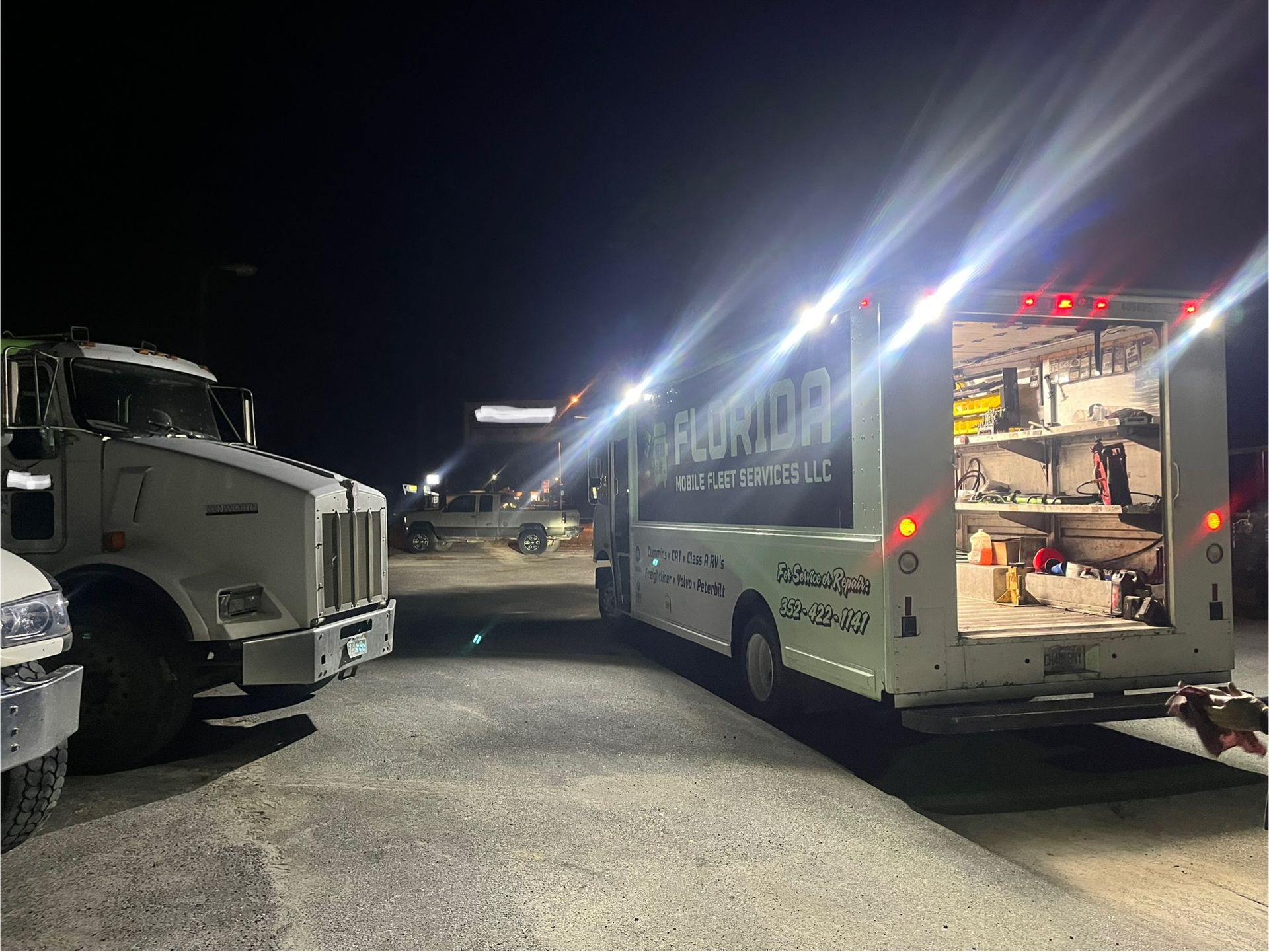 Two trucks are parked next to each other in a parking lot at night.