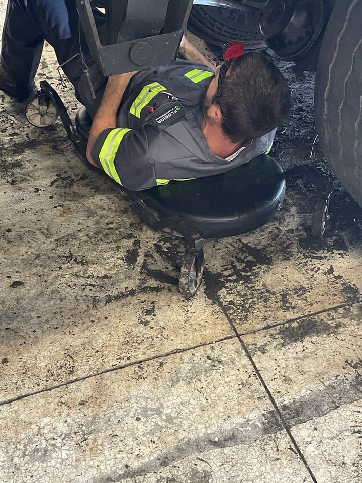 A man is laying on a stool in a garage.