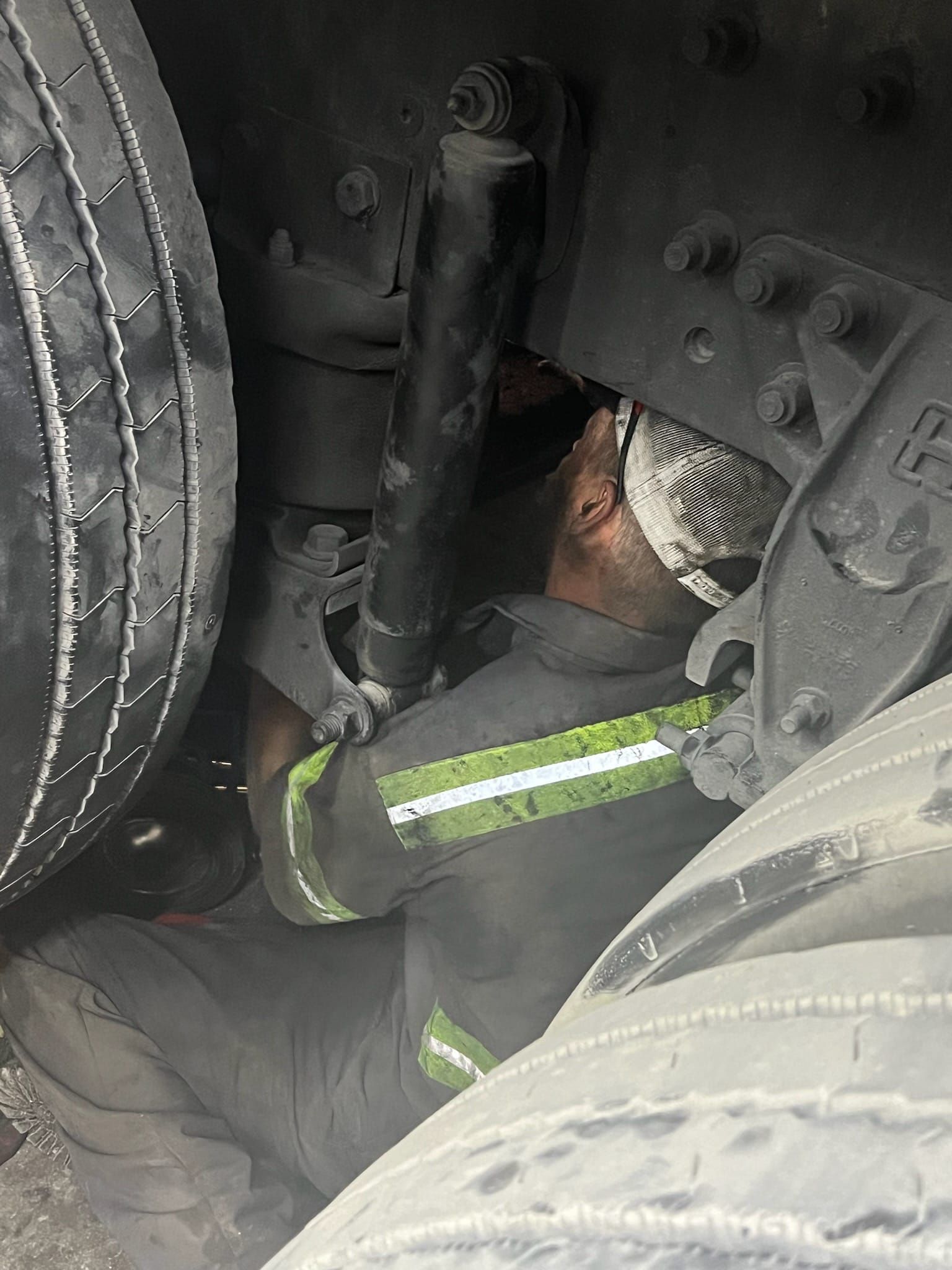 A man is laying on the ground under a truck.