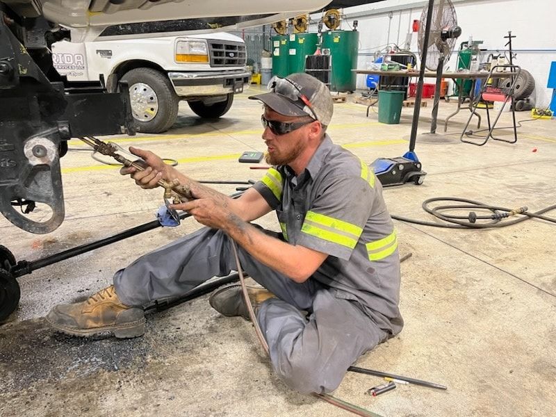 A man is kneeling down in a garage working on a truck.