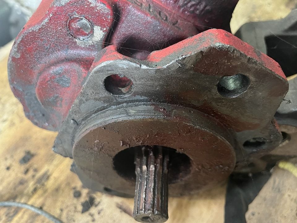 A close up of a red hydraulic pump on a wooden table.