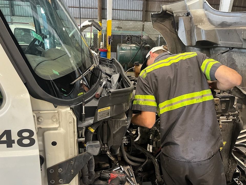 A man is working on the engine of a truck in a garage.