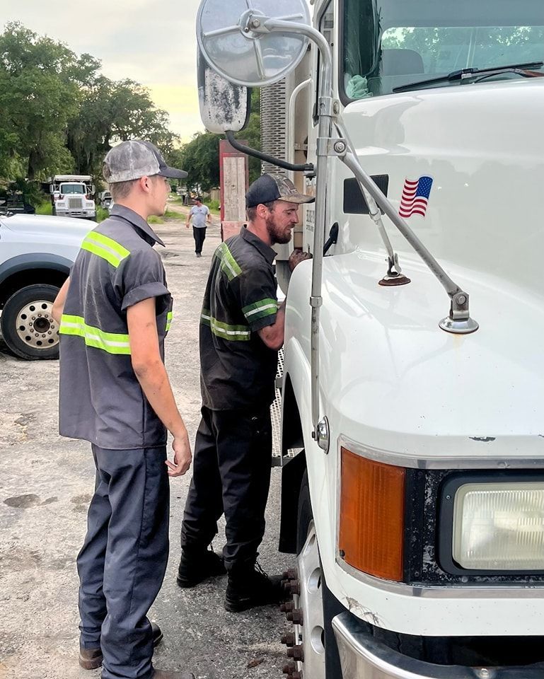 Two men are standing next to a white truck with an american flag on the hood.