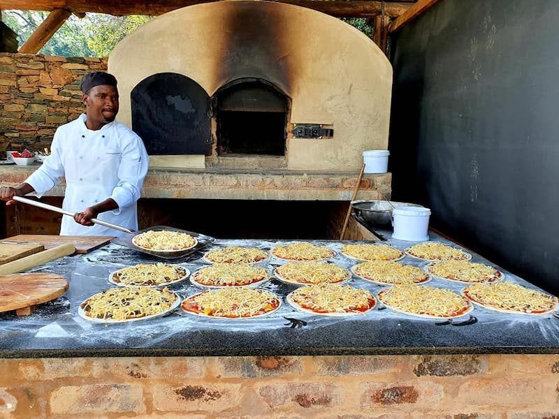 The chef baking pizzas in an outdoor oven at the Summer Kitchen, Riverside Castle for an outdoor event.