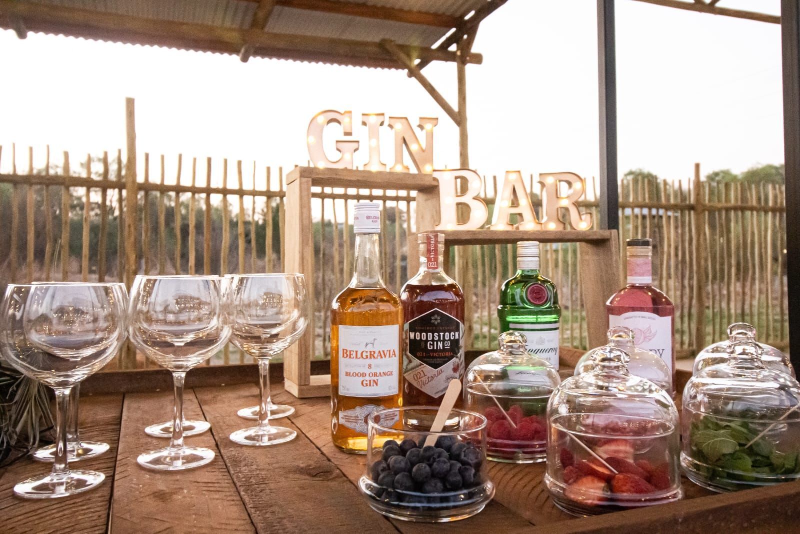 A wooden table topped with bottles of alcohol and wine glasses.