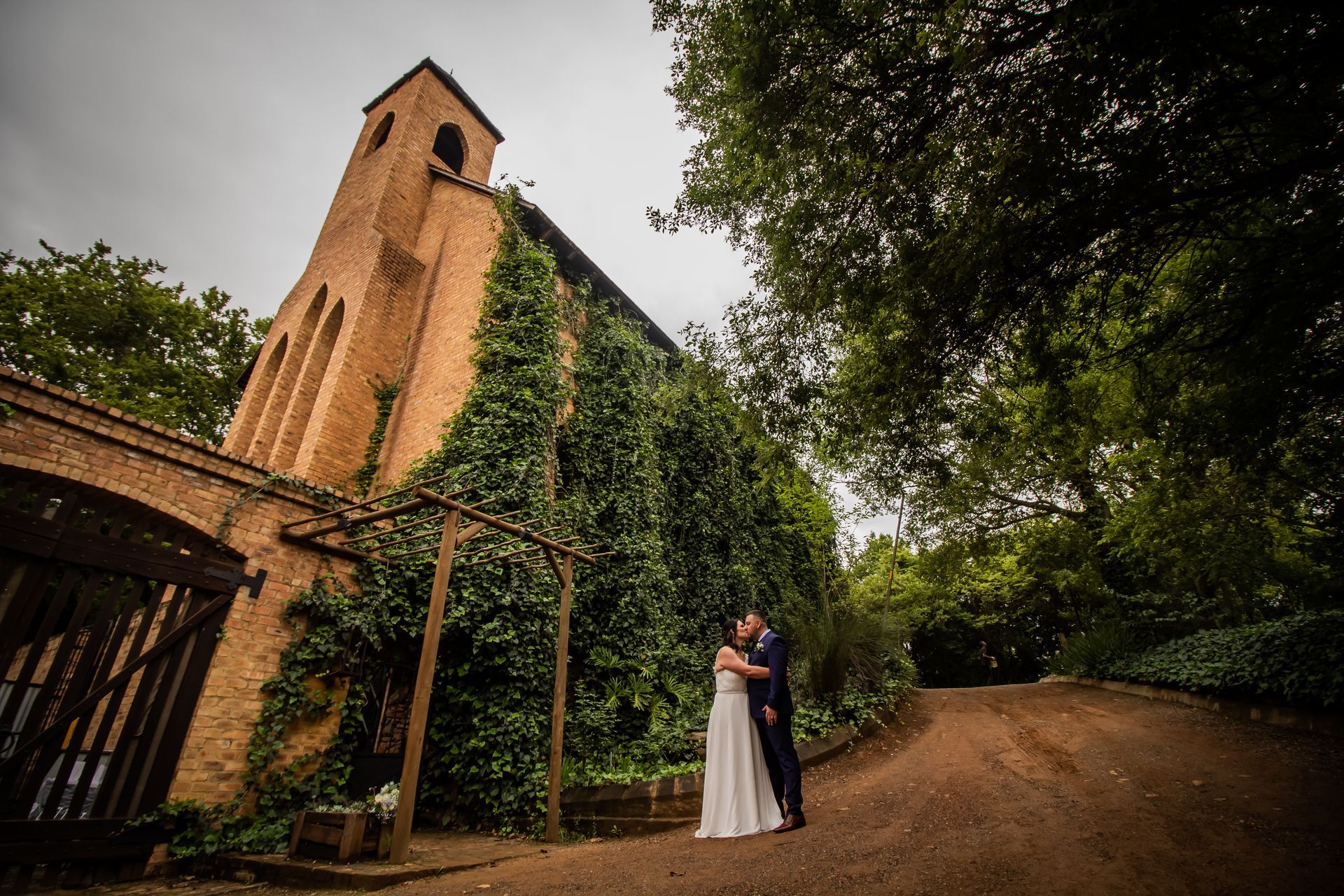 A bride and groom are kissing in front of the chapel at Riverside Castle.