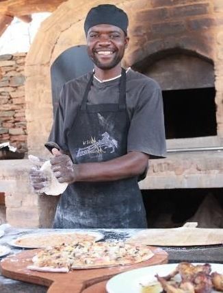 The chef preparing pizzas in an outdoor oven at the Summer Kitchen, Riverside Castle for an outdoor event.