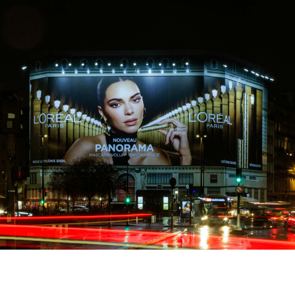 A large billboard for l' oreal paris is lit up at night