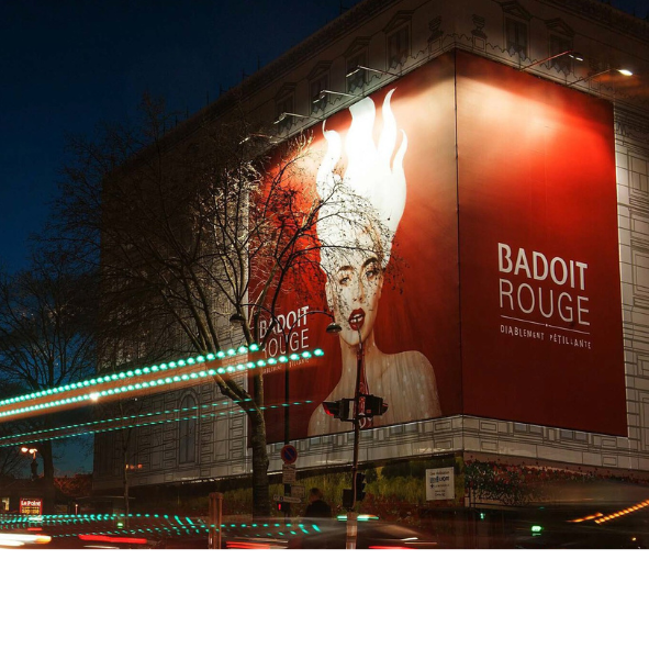 A large billboard on the side of a building that says badoit rouge