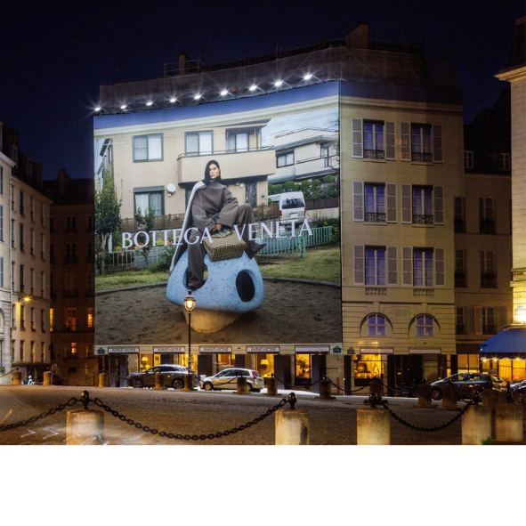 A large billboard on the side of a building advertising bottega veneta