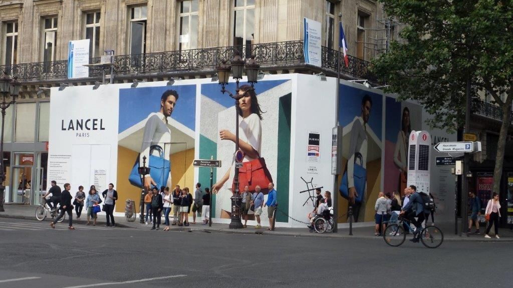A large billboard for lancel is on the side of a building