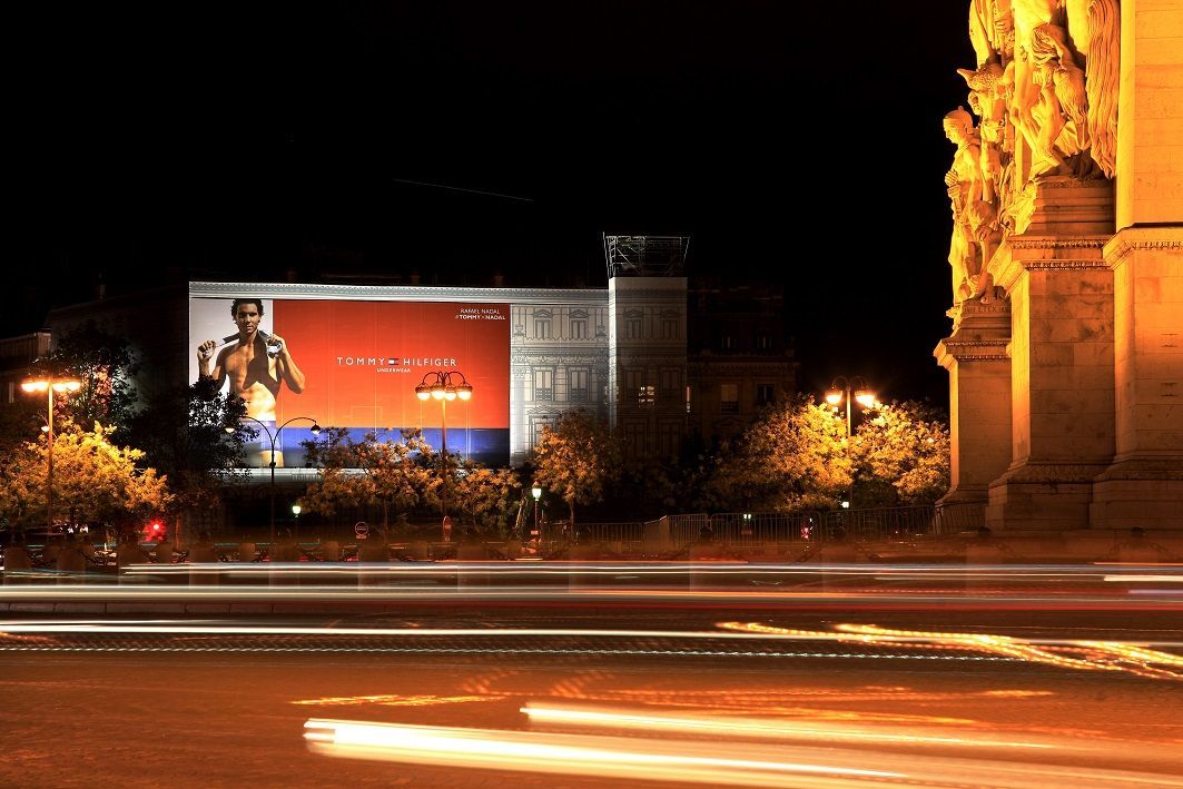 A large billboard is lit up at night in front of a building.
