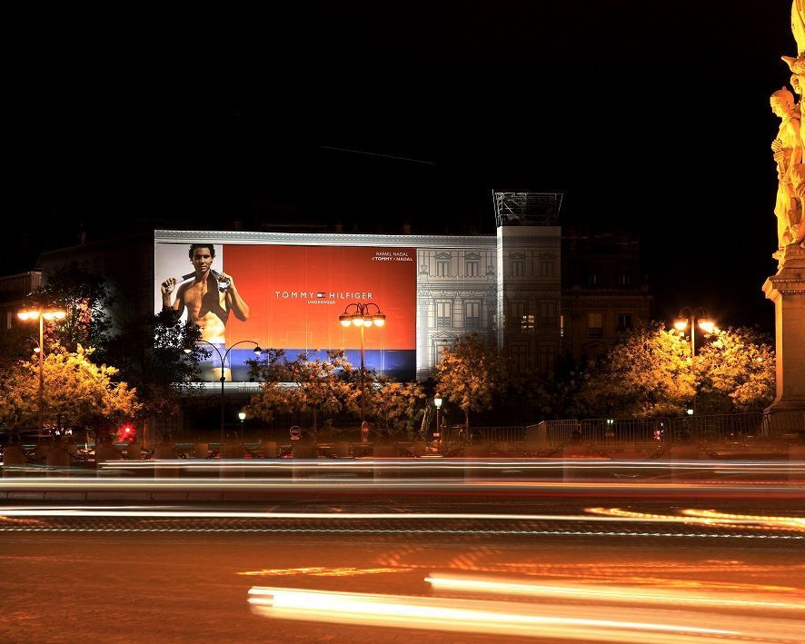 A large billboard with a picture of a man on it is lit up at night