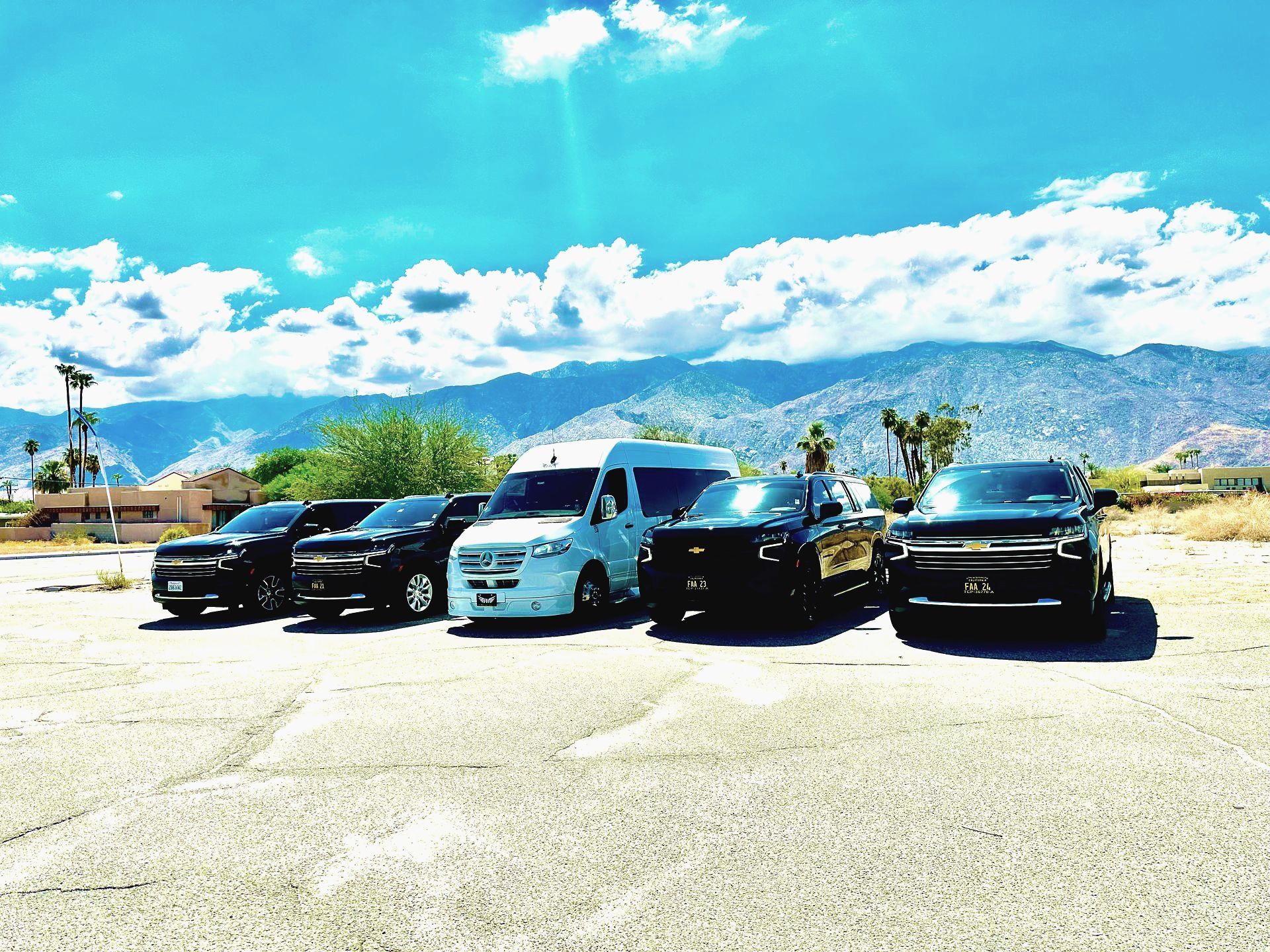a row of cars are parked in a parking lot with mountains in the background .