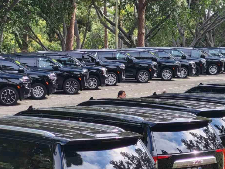 a row of black suvs are parked in a parking lot .