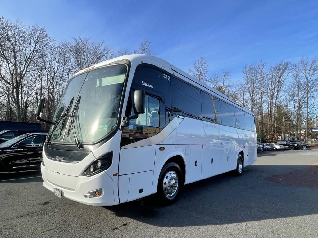 a white bus is parked in a parking lot .