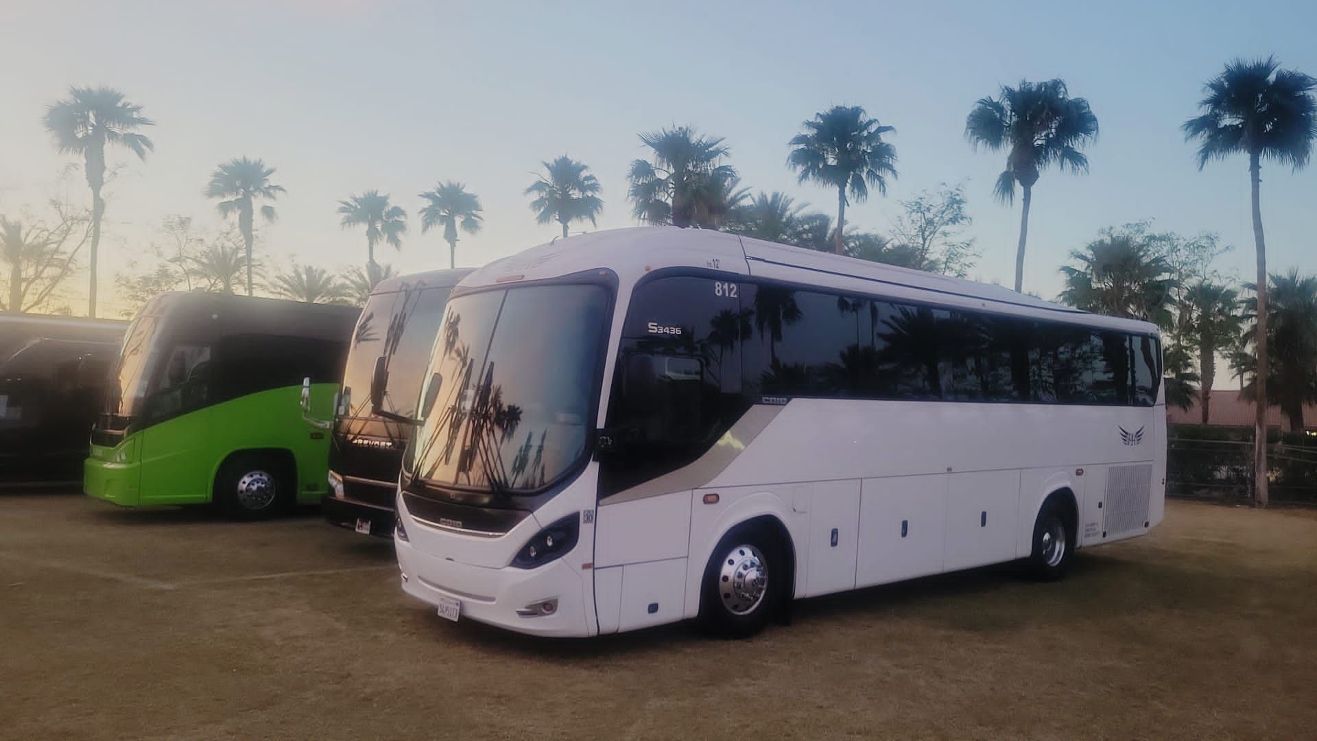 two buses are parked next to each other in a parking lot  at polo grounds FAA Transporattion