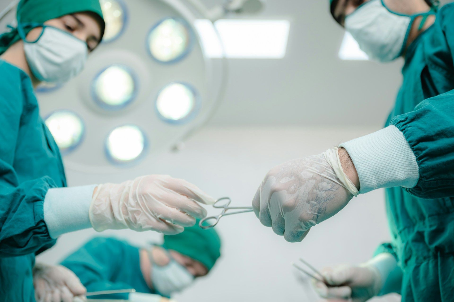 Hospital room with three empty beds, medical equipment, and white walls.