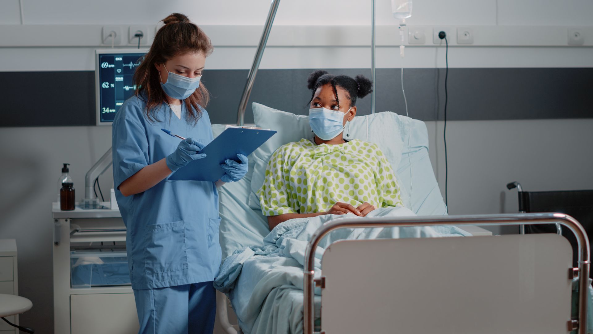 Hands typing on a silver laptop with a stethoscope resting on a wooden desk.