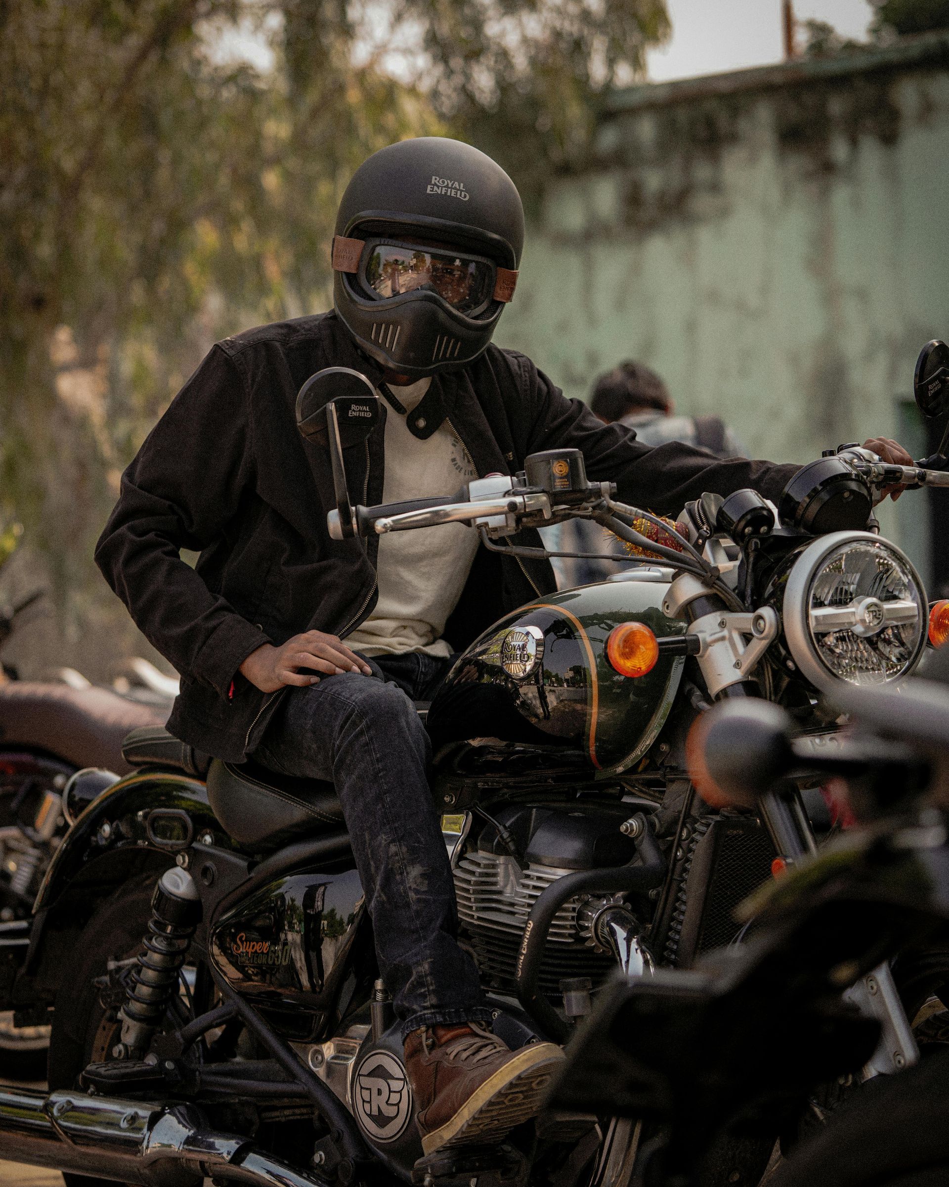 Person in black helmet and jacket on a motorcycle, outdoor setting.