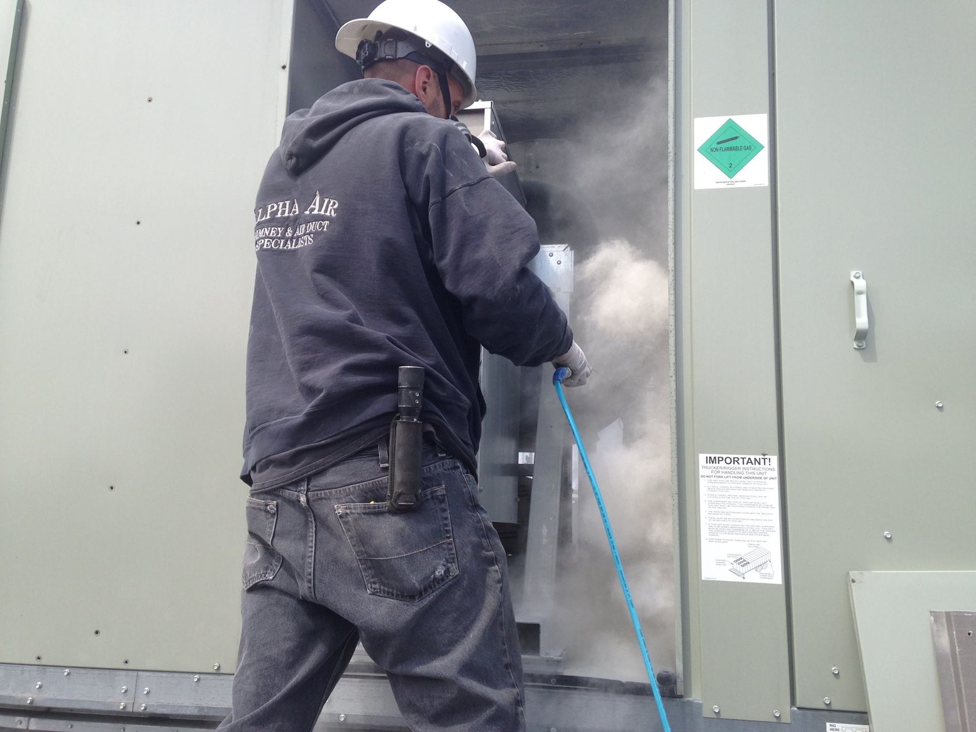 Alpha Air Corporation technician cleaning electrical equipment with dust cloud.