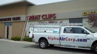 White truck with ladder at a Great Clips store, the sign being worked on.