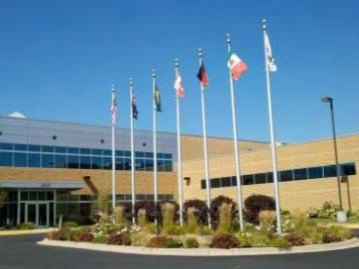 Flags of various countries flying outside a modern building on a sunny day.