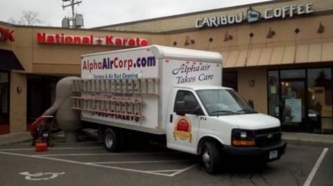 White Alpha Air Corp truck parked near a strip mall with a Karate studio and Caribou Coffee.