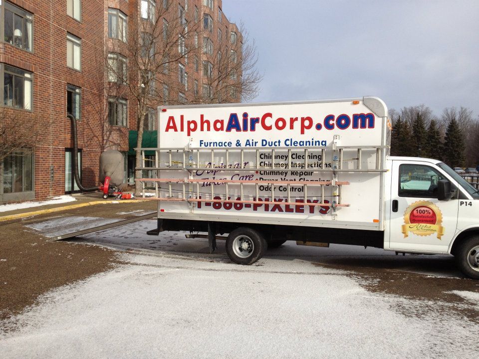 White Alpha Air Corp truck parked in front of a building; ladders on the side.