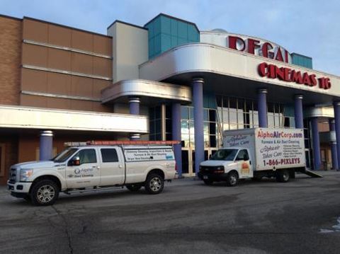 Two Alpha Air Care trucks parked outside the DFGai Cinemas 15 building with a blue and teal facade.