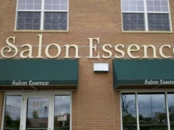 Salon Essence storefront with green awnings and beige letters on brick building.