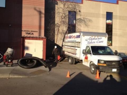 Alpha Air truck parked outside the Blankell Branch YMCA. A worker stands near a large hose and machine.
