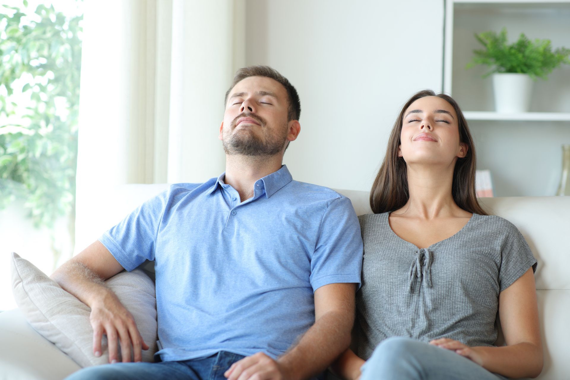 Couple relaxing on sofa enjoying clean indoor air after professional air duct cleaning service.