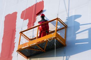 A man in a basket paints the number 17 on a wall