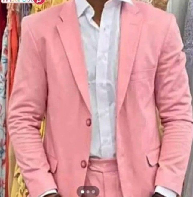 Hombre vestido con un traje rosa claro sobre una camisa blanca.