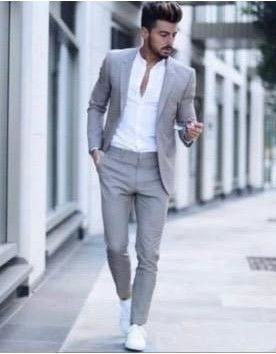 Hombre con traje gris y camisa blanca, caminando al aire libre.