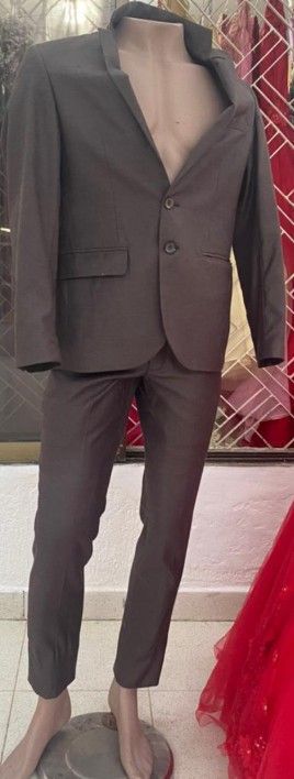 Maniquí con traje gris oscuro. El maniquí se exhibe en interiores y la chaqueta del traje está desabrochada.