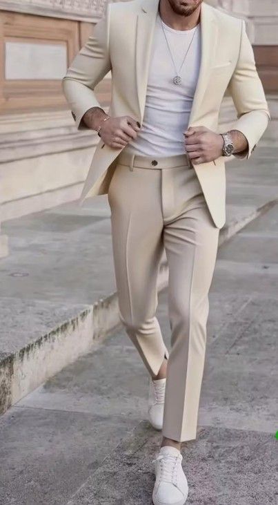 Un hombre con traje color crema y zapatillas blancas sube unas escaleras, ajustándose la chaqueta.