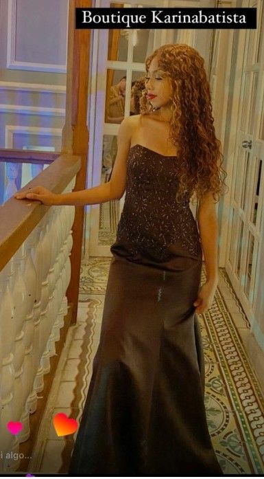 Mujer con un vestido oscuro de gala en una escalera. Tiene el pelo largo y rizado.