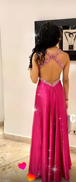 Mujer con un vestido de gala magenta sin espalda; detalles brillantes en los tirantes.
