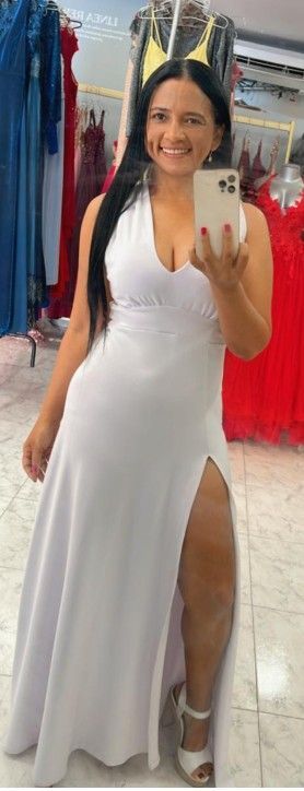 Mujer con vestido blanco de abertura pronunciada, tomándose una selfie frente al espejo en una tienda.