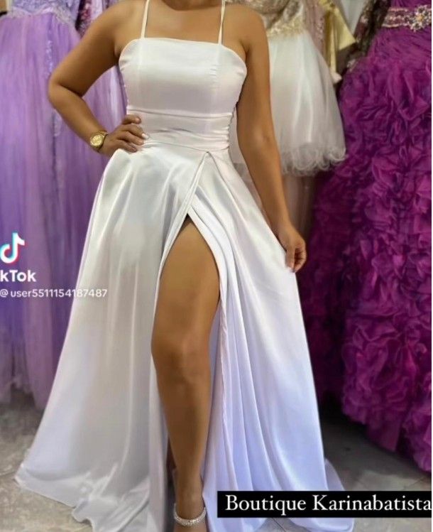 Mujer con un vestido blanco de abertura alta, posando en una boutique.