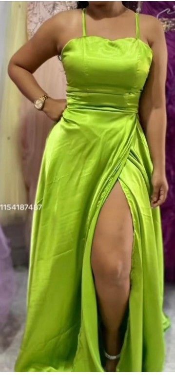 Mujer con un vestido de satén verde lima con una abertura pronunciada. Tiene la mano en la cadera y un reloj en la muñeca.