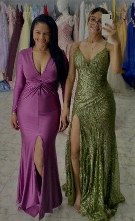Dos mujeres con vestidos de gala; uno magenta, otro verde, ambos con aberturas en las piernas, en una tienda de vestidos.