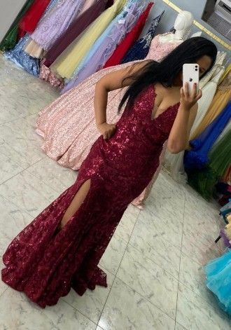 Mujer con un vestido de lentejuelas color burdeos con una abertura pronunciada, tomándose una selfie frente al espejo