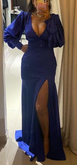 Mujer con un vestido azul con escote en V profundo y abertura alta, en una habitación.