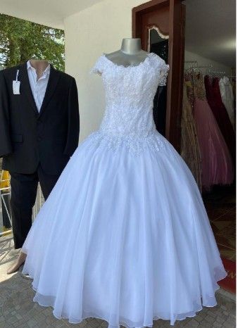 Un vestido de novia blanco sobre un maniquí, con un traje negro sobre otro maniquí al lado.