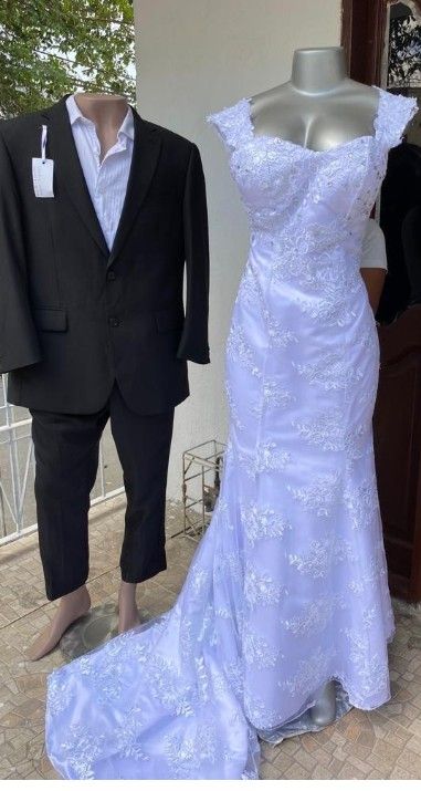 Vestimenta formal: traje negro en un maniquí, vestido de novia blanco de encaje con cola en un maniquí.